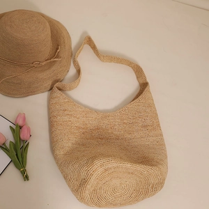 Handwoven raffia hobo shoulder bag in natural beige with matching straw hat and tulips