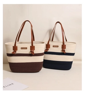 Close-up of woven cotton tote bag with striped base, leather handles and logo plate