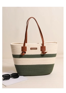 Detail of striped woven tote bag featuring dark green accents and brown leather handles