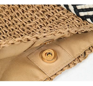 Detail of straw woven beach bag featuring a gold magnetic closure and khaki fabric lining
