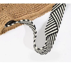 Close-up of brown straw weave texture with black and white striped shoulder strap