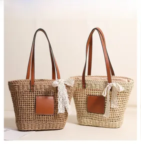 Close-up of woven straw tote bag featuring brown leather patch and white lace bow detail