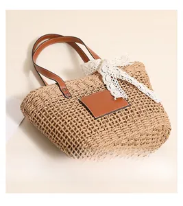 Detail view of woven straw tote bag featuring reinforced brown leather handles and rivets