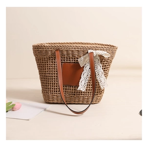 Detail of hollow straw bag with white lace bow and brown leather handle for summer vacation