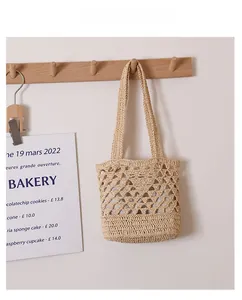 Détail de sac en raphia beige crocheté à la main avec motif ajouré sur crochet bois