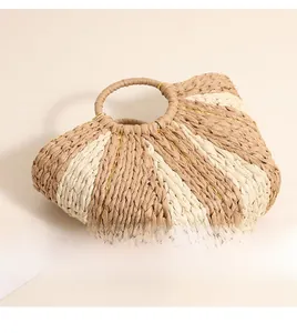 Detail view of woven straw tote bag with contrast stripes and golden thread accents