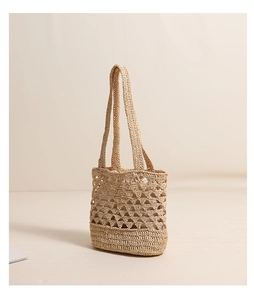 Détails du tissage géométrique ajouré sur le sac bandoulière en raphia beige