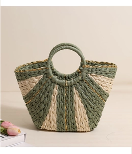 Detail of hand-woven straw bag with green and beige stripes and elegant circular handles