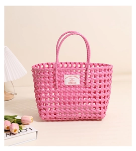 Detailed view of pink woven plastic beach bag featuring a white rectangular logo tag