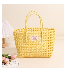 Close-up of yellow hollow plastic woven bag featuring white cloth label on creamy background