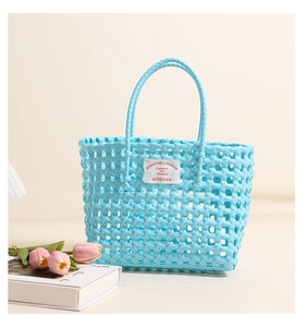 Close-up of light blue woven beach tote with hollow design and white logo patch