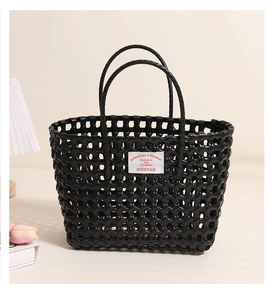 Detail of black hollow-out woven tote bag with artistic studio lighting on desktop
