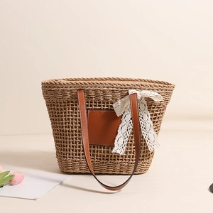 Hollow straw shoulder bag with leather straps and white lace bow detail for beach vacation