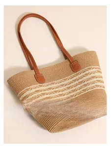 Detailed texture of hand-woven straw tote bag with white wavy patterns and brown leather straps