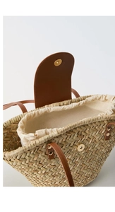 Detail view of woven straw shoulder bag featuring PU leather flap and drawstring lining