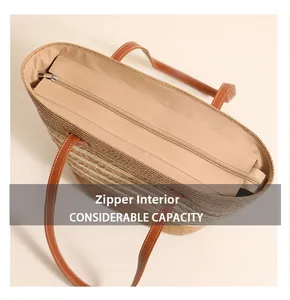 Detail of the zipper lining and brown leather handles on this woven straw tote bag