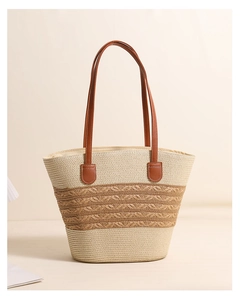 Detailed view of woven straw tote bag with brown leather handles and striped texture