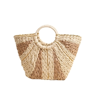 Handmade bicolor straw tote bag with metallic accents and circular handles for beach travel