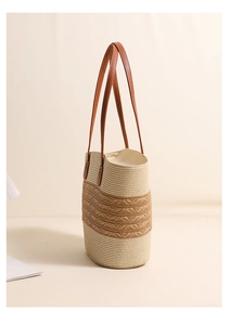 Detail view of woven straw tote bag featuring intricate patterns and leather straps