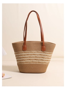 Detailed close-up of brown woven straw tote bag with cream stripes and leather handles