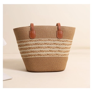 Detail of the woven texture and brown leather handle with metal rivets on the straw bag