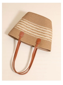 Detail of hand-woven straw tote with white stripes and brown faux leather handles