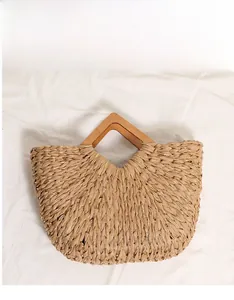 Detailed view of woven straw bag with gold metallic threads and geometric wooden handle