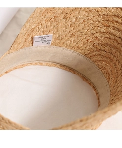 Detailed close-up of 100% natural raffia straw hat interior with premium quality label