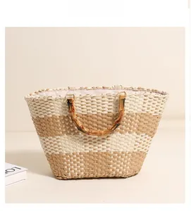 Detailed view of striped straw tote bag featuring faux bamboo handles and pink lining