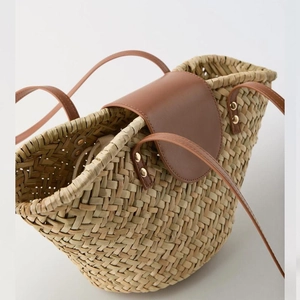 Natural straw woven shoulder bag with brown leather flap and stylish gold rivets