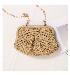 Close-up of handmade straw cloud bag with woven texture and gold chain strap detail