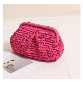 Detail of magenta woven straw clutch bag with textured pleats and soft gathered silhouette