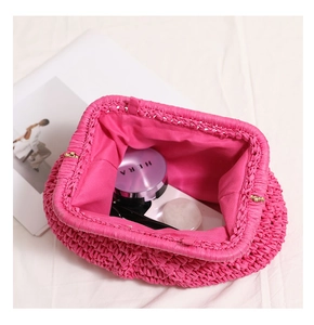 Detail of fuchsia woven straw clutch bag with metal clasp and interior lining