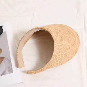 Handwoven raffia open top sun hat with wide brim on white fabric for beach vacation