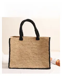 Close-up of natural raffia straw tote bag with black woven edges and top handles