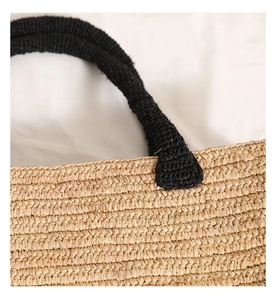 Close-up of natural raffia weaving texture and black crochet handle on a tote bag