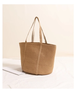 Macro detail showing natural woven texture and slim shoulder straps of the straw tote bag