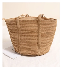 Close-up of khaki woven straw tote bag featuring horizontal texture and zip closure