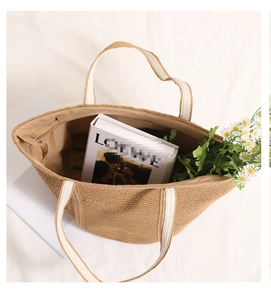 Close-up of woven straw tote bag with canvas handles and interior zipper pocket detail