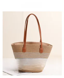 Detail view of woven straw tote bag with striped pattern and leather shoulder straps