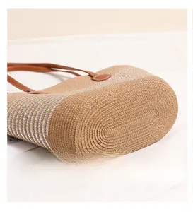Detailed view of the oval straw base and silver stripes of the woven tote bag