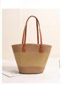Detail of a woven straw beach bag featuring bright yellow stripes and brown leather handles
