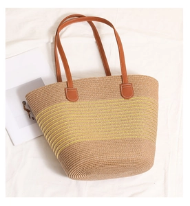 Close-up of woven straw tote bag with yellow striped patterns and brown faux leather handles
