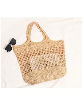 Detail view of large straw tote bag with hollow woven pattern and top handles