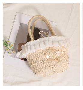 Close-up of corn husk woven bag featuring delicate white lace trim and satin bows