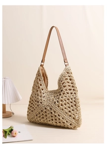Detail of hollow-out beige straw hobo bag with brown leather strap on aesthetic background
