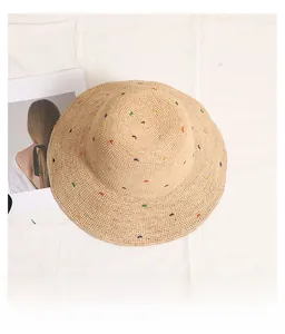 Détail d'un chapeau de soleil en raphia avec des points brodés colorés et tissés