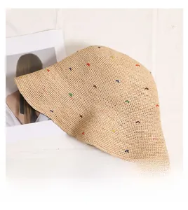 Détail du chapeau de paille en raphia avec broderies papillons colorées et texture tissée