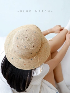Détail d'un chapeau en raphia avec broderie colorée et décoration de nœud assortie