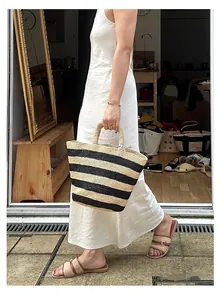 Lifestyle shot of a striped raffia tote bag with matching woven sandals and white dress